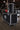 A ATA 55" - 65" black abs single universal LCD / LED monitor road case with 1/2" ply a pull-off lid, adjustable monitor width, Accessory compartment and heavy-duty casters, displayed in a warehouse setting. 