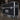 A ATA 55" - 65" black abs single universal LCD / LED monitor road case with 1/2" ply a pull-off lid, adjustable monitor width, Accessory compartment and heavy-duty casters, displayed in a warehouse setting. 